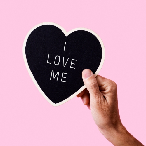 a pink background with a black heart with 'I love me' written on it