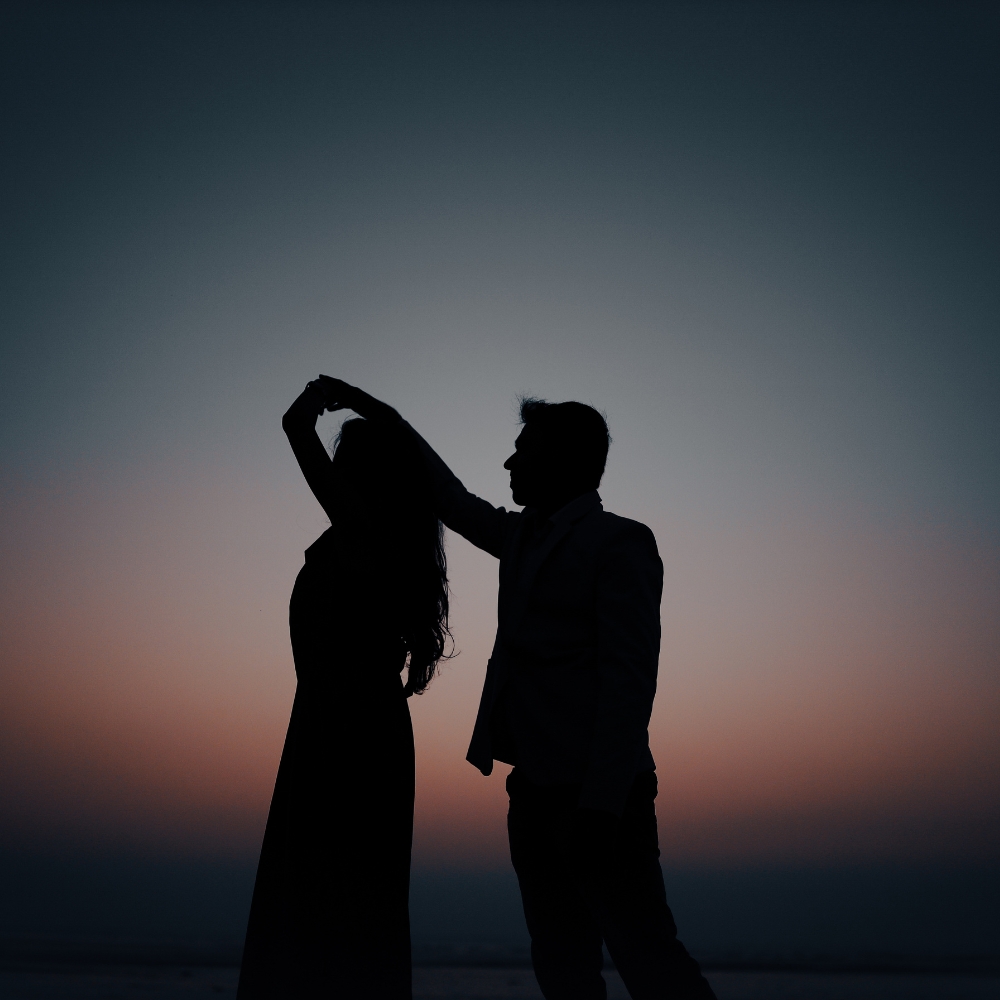 silhouette of man and woman dancing infront of sunset